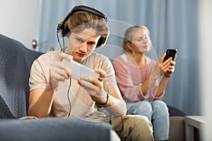 Modern teenager engrossed in mobile online phone game at home