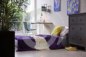 Modern teenager`s room interior with comfortable bed, workplace and stylish design elements