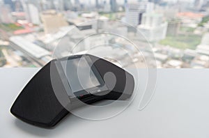 Modern telephone IP conferance device on the white table with city scape view for teleconferance technology concept