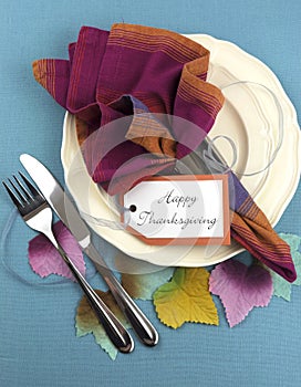 Modern Thanksgiving dining table place setting with autumn leaves - vertical