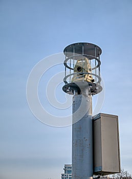 Modern theodolite geodesy equipment in security cage on tall column