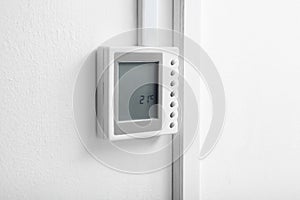 Modern thermostat on white wall
