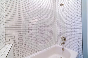 Modern tiled white bathtub with shower bright interior