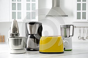 Modern toaster and other home appliances on white marble table in kitchen