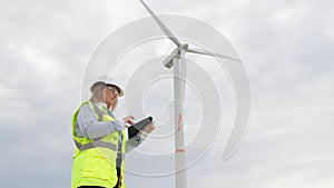 Modern tools for a sustainable future: a tablet and a windmill in the hands of a female scientist are the key to green