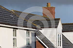 Modern town house roof with slate tiles, chimney and white dormer window