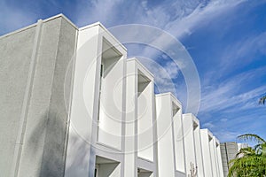 Modern townhome facade with flat roof and projecting window frames against sky