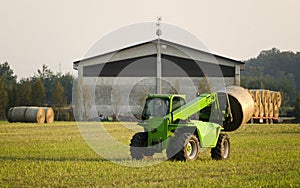 Modern tractor moving hay bales