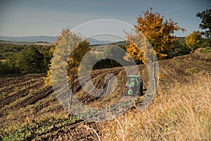 a modern tractor plows the fields in autumn weather