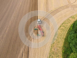 Modern tractor working on the agricultural field - aerial view  of a tractor plowing and sowing in the agricultural field - high