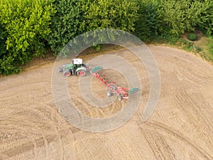 Modern tractor working on the agricultural field - aerial view  of a tractor plowing and sowing in the agricultural field - high