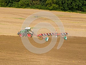 Modern tractor working on the agricultural field - aerial view  of a tractor plowing and sowing in the agricultural field - high