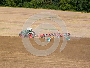 Modern tractor working on the agricultural field - aerial view  of a tractor plowing and sowing in the agricultural field - high