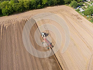 Modern tractor working on the agricultural field - aerial view  of a tractor plowing and sowing in the agricultural field - high