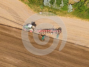 Modern tractor working on the agricultural field - aerial view  of a tractor plowing and sowing in the agricultural field - high