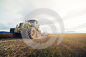 Modern tractor working on the farm, a modern agricultural transport, cultivation of fertile land, tractor on cloudy sky background