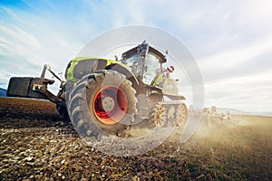 Modern tractor working on the farm, a modern agricultural transport, cultivation of fertile land, tractor on cloudy sky background