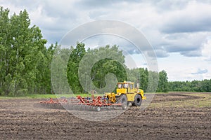 Modern tractor working on field in summer, preparing soil for sowing with seedbed cultivator. Agricultural machinery, farming
