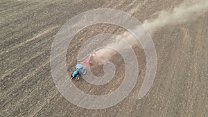 Modern tractor working plowing and sowing on the agricultural field - aerial view - high top view