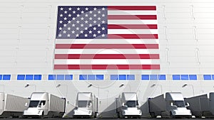 Modern trailer trucks load or unload at warehouse bays with flag of the USA. American logistics related conceptual 3D