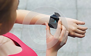 Modern training with device and activity monitoring. Over shoulder view of athletic lady using fitness tracker