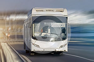 Modern transport bus on asphalt rides at high speed, front view.