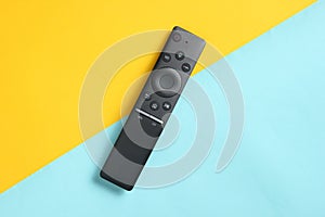 A modern TV remote control on pastel background. Top view, minimalism.