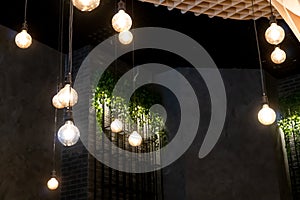 Modern and unusual interior design in the restaurant with the execution of lamps suspended on long wires. Cozy and calm design in
