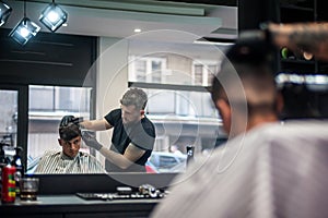 Modern urban hairdresser cut hair with hair trimmer in professional hairdressing salon