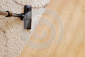 Modern vacuum cleaner on a beige carpet wooden parquet.