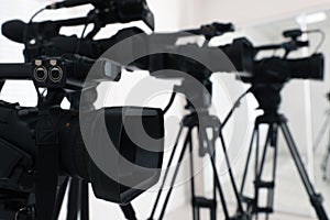 Modern video camera indoors, focus on lens. Professional media equipment for broadcasting event