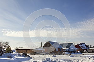 Modern village houses under a blue sky with white clouds in winter landscape