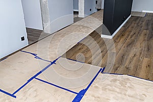 Modern vinyl panels imitating wood in the living room, covered with corrugated cardboard to protect them against damage.