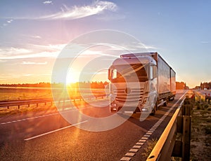 Modern wagon truck transports cargo against the backdrop of a sunset. The concept of truck drivers in the field of freight and