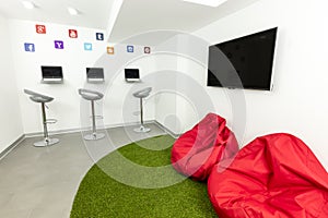 Modern waiting, or lounge room; laptops, TV and beanbags in the background