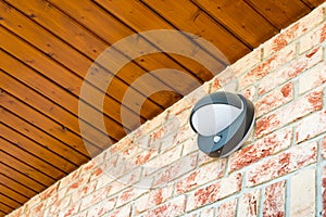 Modern wall lamp with motion and light sensor on the brick wall