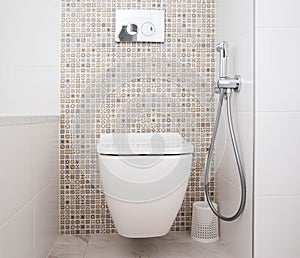 Modern wall-mounted toilet with shower for private spaces. White and clean bathroom