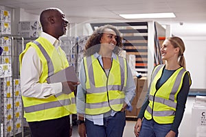 Modern Warehouse With Fulfilment Staff Picking Items From Shelves And Manager Using Digital Tablet