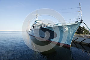 Modern warship in the bay with sailing ship in background