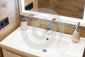 Modern washbasin with chrome faucet beside a stylish soap dispenser
