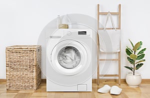 Modern washing machine with basket in laundry room interior