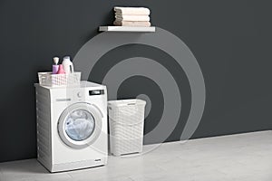 Modern washing machine, laundry basket and shelf with towels in bathroom