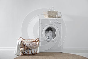 Modern washing machine and laundry baskets near white wall. Bathroom interior
