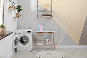 Modern washing machine in laundry room interior