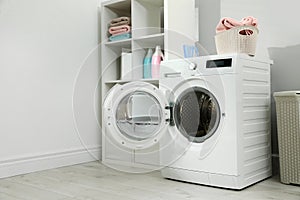 Modern washing machine in laundry room interior