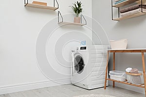 Modern washing machine in laundry room interior