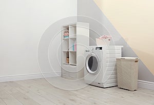 Modern washing machine in laundry room interior