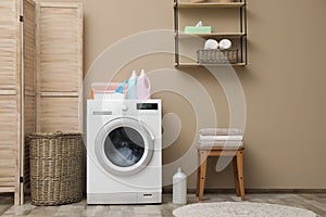 Modern washing machine near color wall in laundry room interior