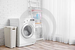 Modern washing machine near wall in laundry room interior, space for text