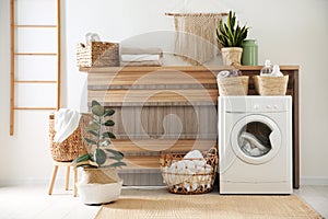 Modern washing machine and plants in laundry room